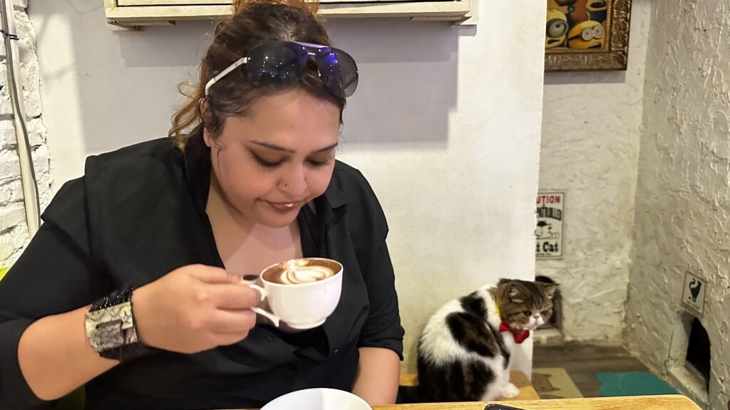 My sister having coffee with a cat seated beside her at Caturday Cafe Bangkok
